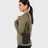 A woman wearing a green sweatshirt and a black crossbody bag. Produktbild-Vorschau