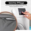 A close-up of a dog bed cover with a zipper, next to a washing machine with a hand pressing buttons. Produktbild-Vorschau