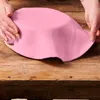 Hands are shown covering a pink fondant cake topper on a wooden table. Produktbild-Vorschau