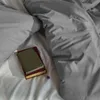 A close-up view of bedding with two books and a small purple flower. Produktbild-Vorschau