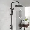 A black shower system mounted on a white tiled wall in a modern bathroom. Anteprima dell’immagine prodotto