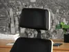 Close-up of the headrest of a black office chair with wooden accents, placed on a desk with books and a plant in the background. Voir les images du produit