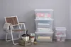 A collection of storage boxes, a chair, and some decorative items are arranged against a gray wall. Anteprima dell’immagine prodotto