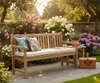 A wooden garden bench with cushions and pillows sits in a blooming garden with roses and hydrangeas. Produktbild-Vorschau
