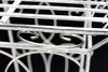 A close-up view of a white metal plant stand with decorative scrollwork. Anteprima dell’immagine prodotto