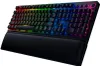 A black gaming keyboard with RGB lighting and a wrist rest, shown from a diagonal angle against a white background. Produktbild-Vorschau