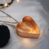 A close-up of a heart-shaped LED light on a white, silky surface. Produktbild-Vorschau