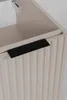 A close-up view of a ribbed cabinet door with a black handle. Produktbild-Vorschau