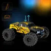 A remote-controlled monster truck with yellow and black graphics, shown against a dark background with blue and orange lighting effects. Voir les images du produit