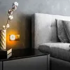 A night light plugged into a wall socket next to a bed. Produktbild-Vorschau