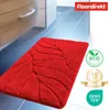 A red bath mat with a leaf pattern is shown on a tiled floor next to a cabinet. Produktbild-Vorschau