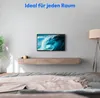 A TV mounted on a wall above a wooden entertainment unit in a bedroom setting. Produktbild-Vorschau