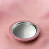 A round, pink-rimmed mirror on a pink fabric background. Podgląd zdjęcia produktu