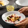 A person is holding a bowl of yogurt with fruit and a pastry. Produktbild-Vorschau