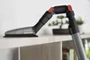 A close-up shot of a vacuum cleaner attachment with a flexible hose on a white shelf. Produktbild-Vorschau
