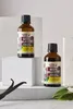 Two bottles of vanilla extract are displayed on white blocks, with vanilla beans and leaves in the foreground. Náhľad obrázku produktu