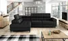 A modern living room with a black sectional sofa, a wooden dresser, a coffee table, and a large window overlooking a city. Náhled obrázku produktu