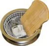 A stainless steel sink basin with a white wire rack, a wooden cutting board, and a package of plumbing parts inside. Produktbild-Vorschau