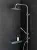 A modern shower set with a rain shower head and a handheld shower head, mounted on a dark tiled wall. A soap dispenser sits on a shelf below. Produktbild-Vorschau