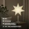 A white star-shaped lamp is placed on a bedside table next to a sofa and a plant. Information icons are overlaid on the left side of the image. Podgląd zdjęcia produktu