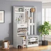A white entryway organizer with a bench, shelves, drawers, and hooks, set against a light gray wall and a window with greenery outside. Podgląd zdjęcia produktu
