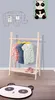 A children's clothing rack with clothes hanging on it, placed in a room with wall decorations and a rug. Produktbild-Vorschau