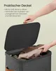 A hand is shown opening the lid of a dark gray laundry basket, revealing a brown fabric item inside. Produktbild-Vorschau