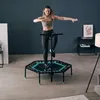 A woman is exercising on a mini-trampoline in a room. Voir les images du produit