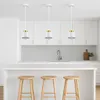 Three pendant lights hang above a kitchen island with stools. Náhled obrázku produktu
