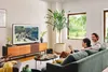 A couple relaxing on a couch in a modern living room, watching TV. Voir les images du produit