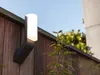 An outdoor wall light mounted on a wooden fence. Produktbild-Vorschau