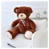 A large brown teddy bear sitting on a cream-colored armchair. Podgląd zdjęcia produktu