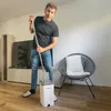 A man is holding a mop and bucket in a living room. Podgląd zdjęcia produktu