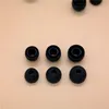 A collection of black silicone earbud tips arranged in rows on a light beige background. Produktbild-Vorschau