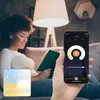 A woman is reading a book in a dimly lit room, with a smart lamp and a smartphone app controlling the light. Produktbild-Vorschau