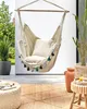 An outdoor patio scene with a hanging chair, plants, and furniture. Náhled obrázku produktu