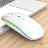 A white wireless mouse with RGB lighting is placed on a wooden surface next to a laptop. Produktbild-Vorschau