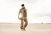 A man in desert attire stands in a sandy landscape. Produktbild-Vorschau