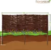 A woven willow garden border with stakes, shown partially buried in the ground with flowers in front. Produktbild-Vorschau
