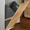 A close-up view of a gray fabric laundry basket with wooden accents, partially open. Anteprima dell’immagine prodotto