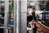 A person is using a Bosch rotary hammer drill to drill into a metal stud. Voir les images du produit