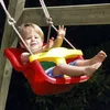 A young child is sitting in a red and yellow baby swing. Produktbild-Vorschau
