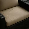 Close-up of a beige cushion on a black wicker chair, with water droplets on the cushion. Podgląd zdjęcia produktu
