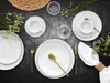 A table setting with white plates, cups, and gold cutlery, decorated with dried flowers. Produktbild-Vorschau