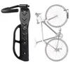 A black bicycle wall mount is shown on the left, and a bicycle is shown hanging on a similar mount on the right. Náhled obrázku produktu