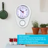 A kitchen wall with a clock, a hanging pan, plants, and cans. Náhled obrázku produktu