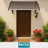 A brown door with a dark gray awning above it, flanked by potted plants with yellow and red flowers. Náhled obrázku produktu
