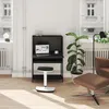 A modern home office setup with a black secretary desk, laptop, and stool, next to a brown armchair and a large plant. Produktbild-Vorschau