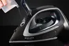 A hand is pouring liquid into a black and silver cordless steam iron against a black background. Produktbild-Vorschau