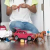 A child playing with toy cars and horses on a wooden floor. Produktbild-Vorschau